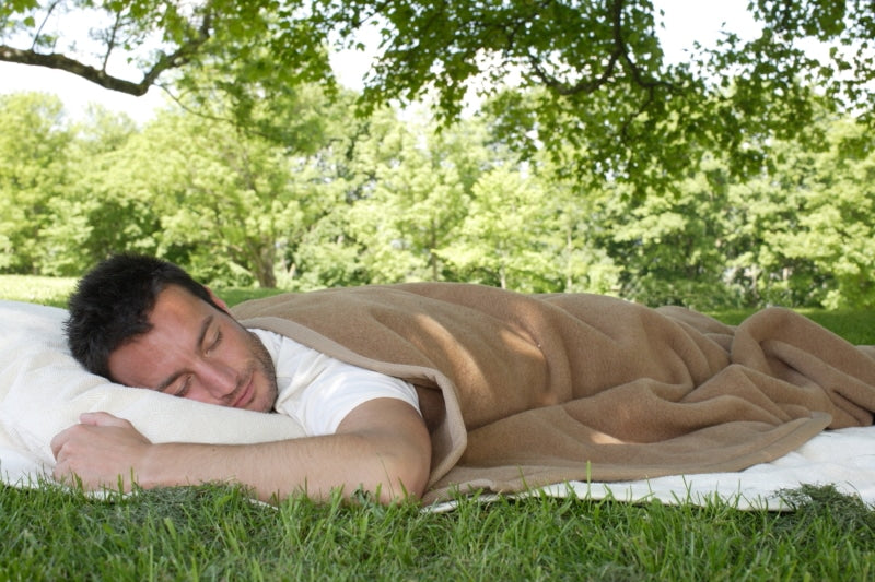 Model schläft im Gras mit Maharadscha Kamelhaardecke