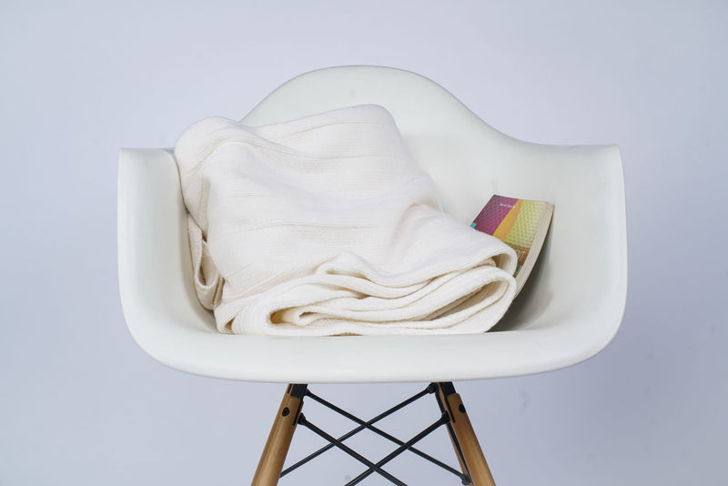 Gefaltetes Estoril Strickplaid in weiß auf dem Stuhl