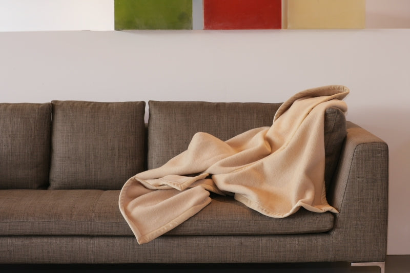 Maharani Kamelhaardecke in creme auf braunem Sofa