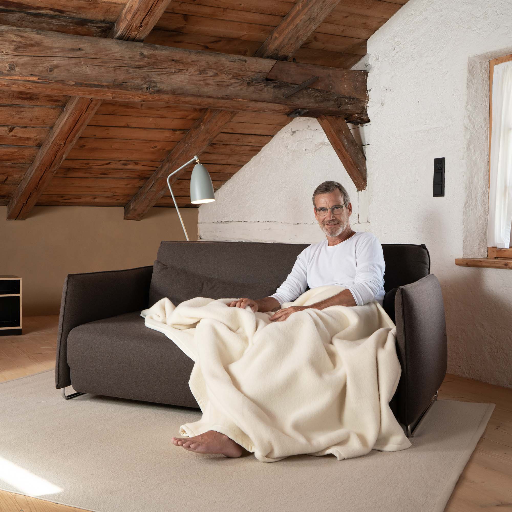 Perulama Alpakadecke 80% Alpaka 20% Schurwolle Farbe weiß Ritter Decken Mann auf Sofa mit Decke