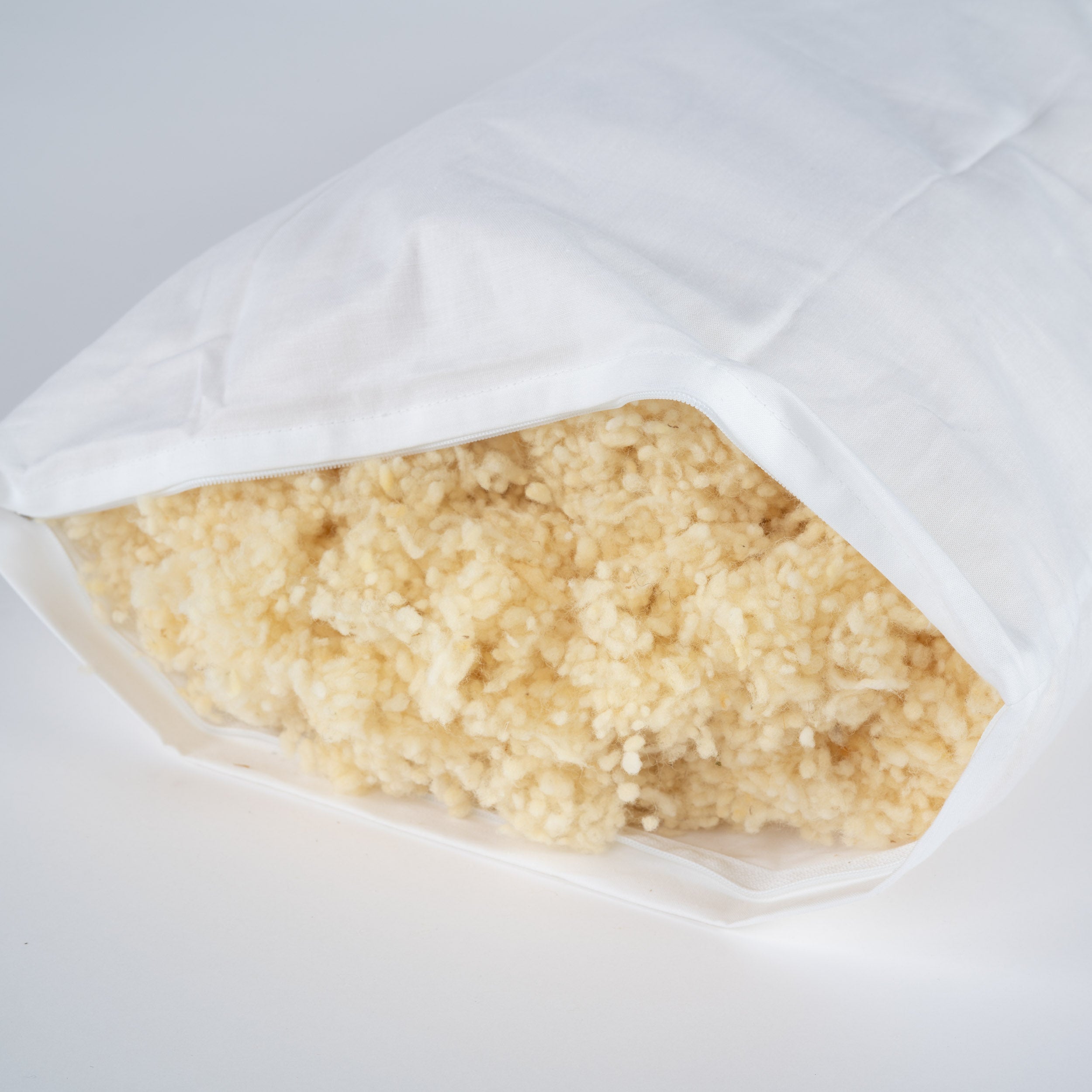 Geöffnets Inlett Kissen mit einer Füllung aus weichen, naturfarbenen Schurwollkügelchen