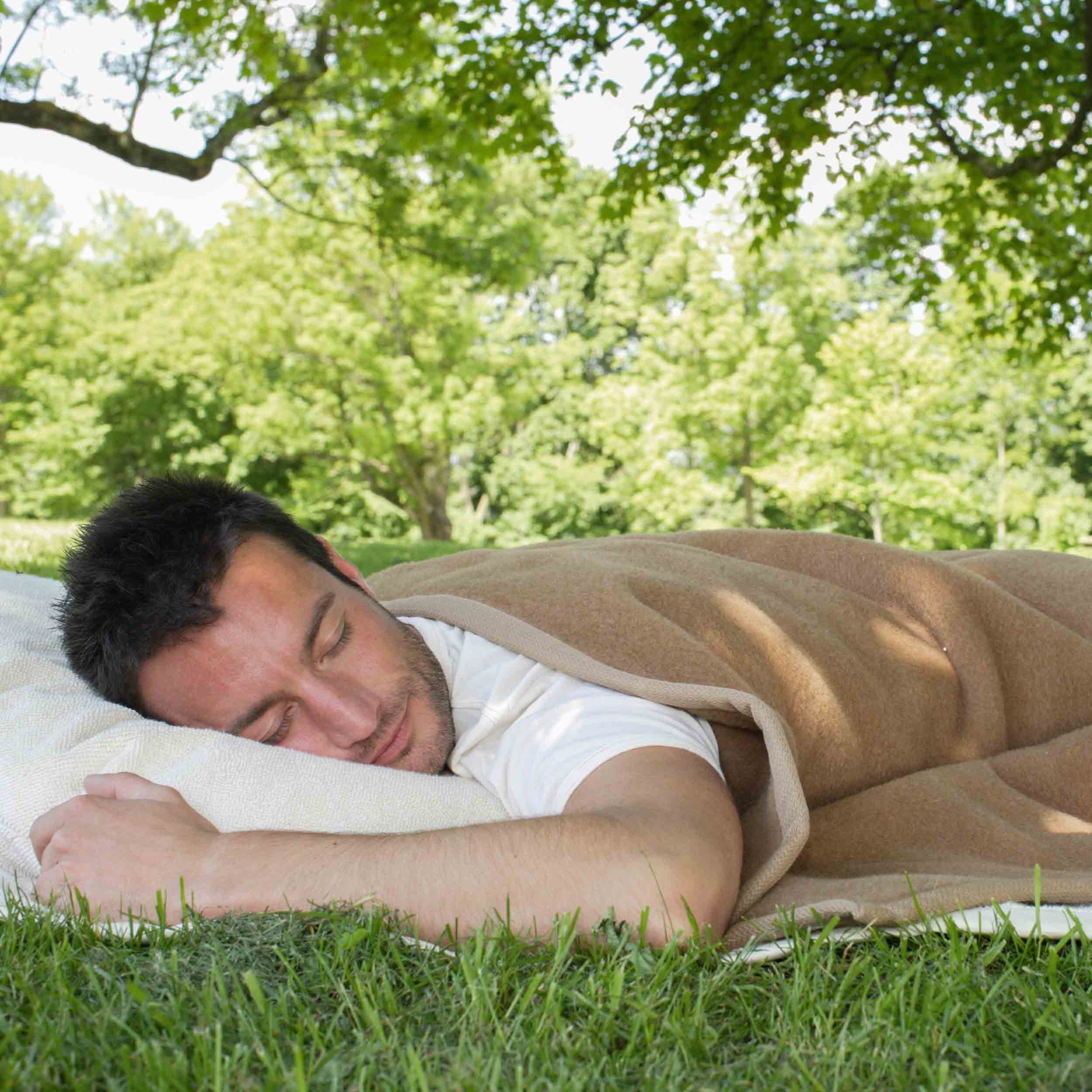Model schläft im Gras mit Maharadscha Kamelhaardecke
