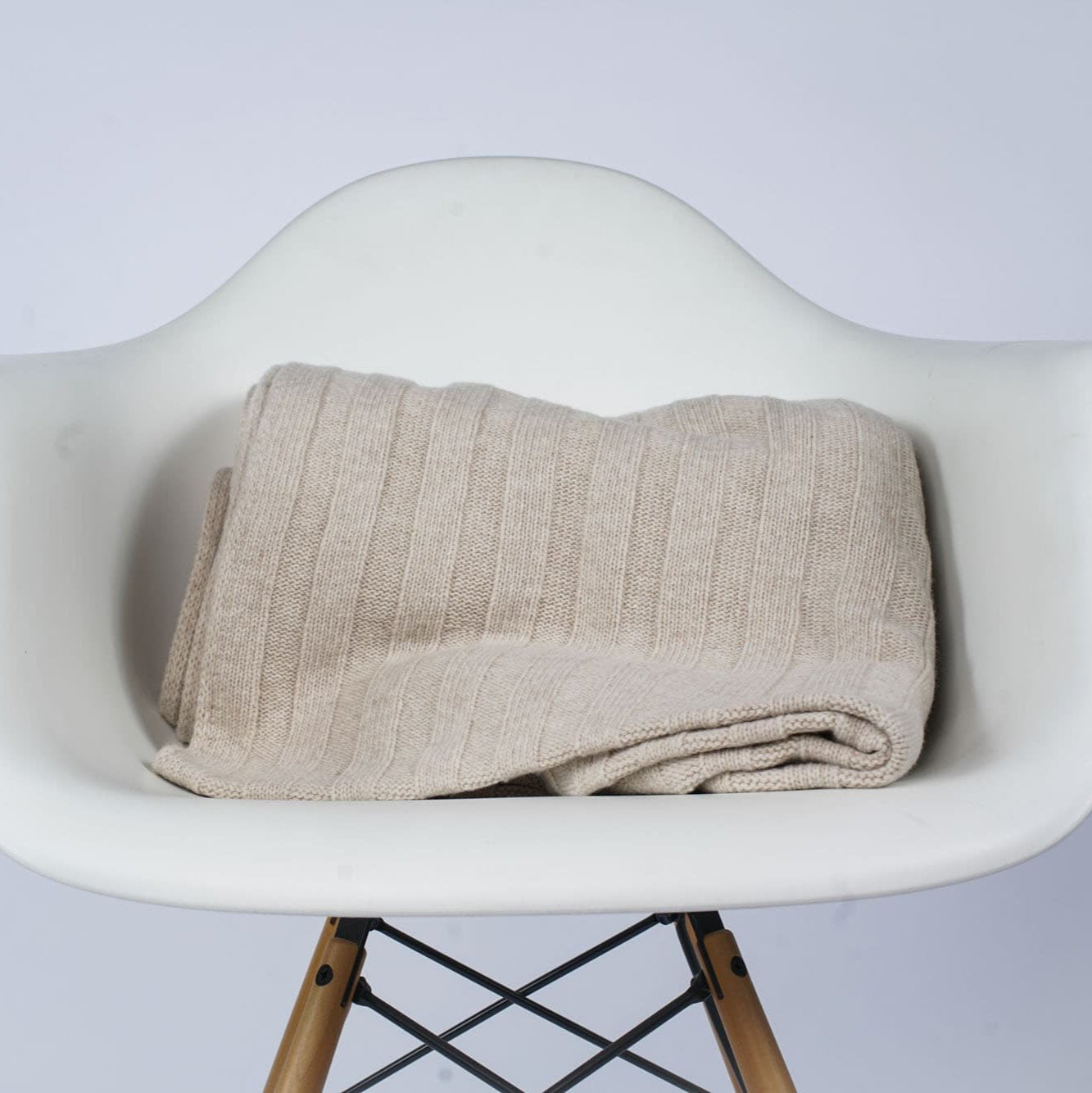 Gefaltetes Estoril Strickplaid in creme auf dem Stuhl Strickdecke Schurwolldecke