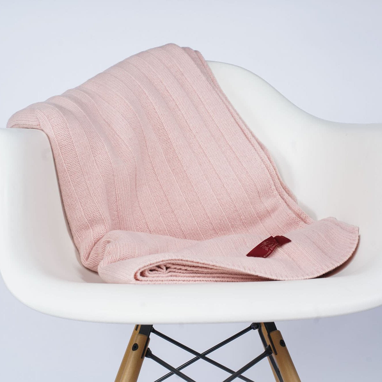 Gefaltetes Estoril Strickplaid in rosa auf dem Stuhl