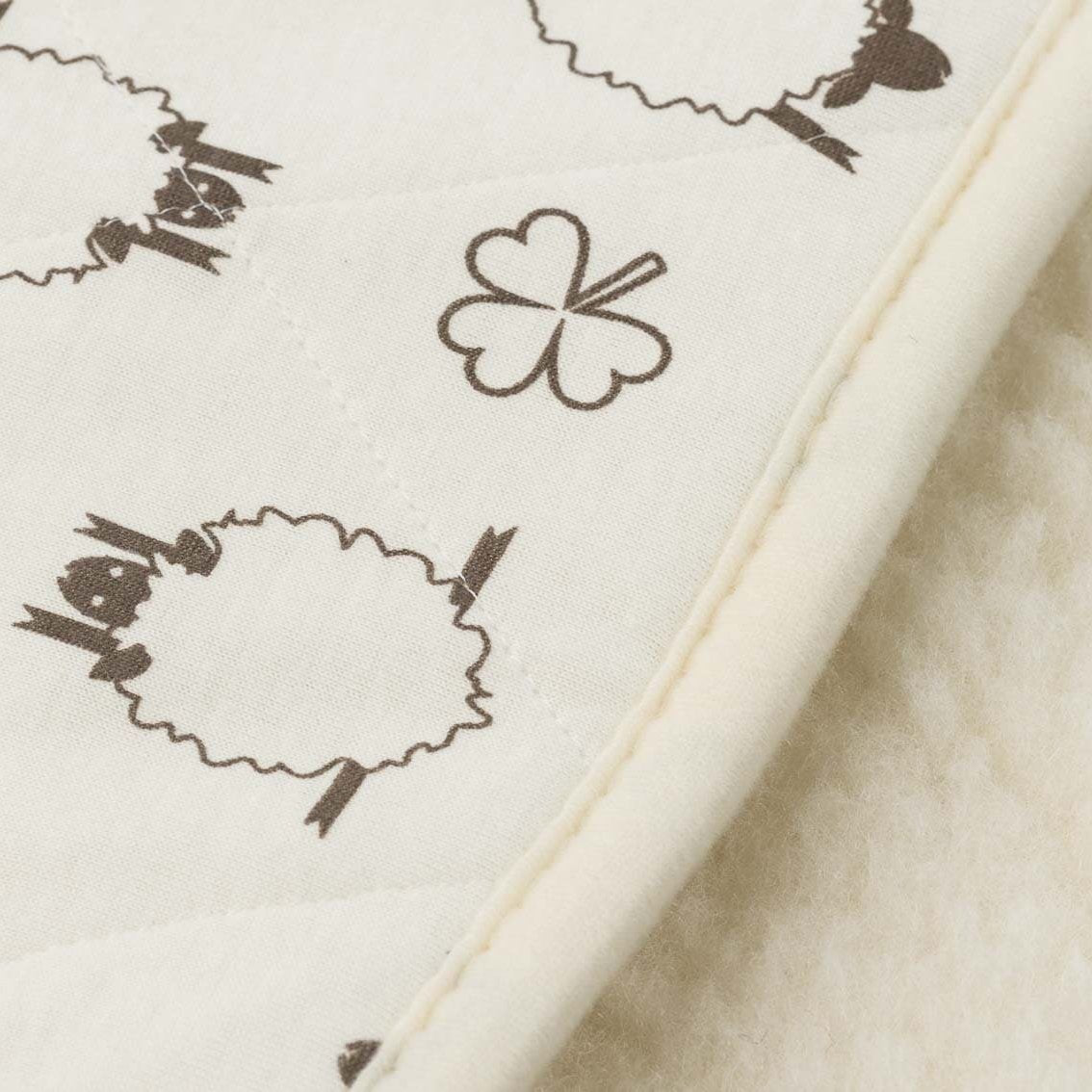 Alpin Kinder Wollflor Bettdecke in naturweiß mit Schaf- und Kleeblattmuster im Detail