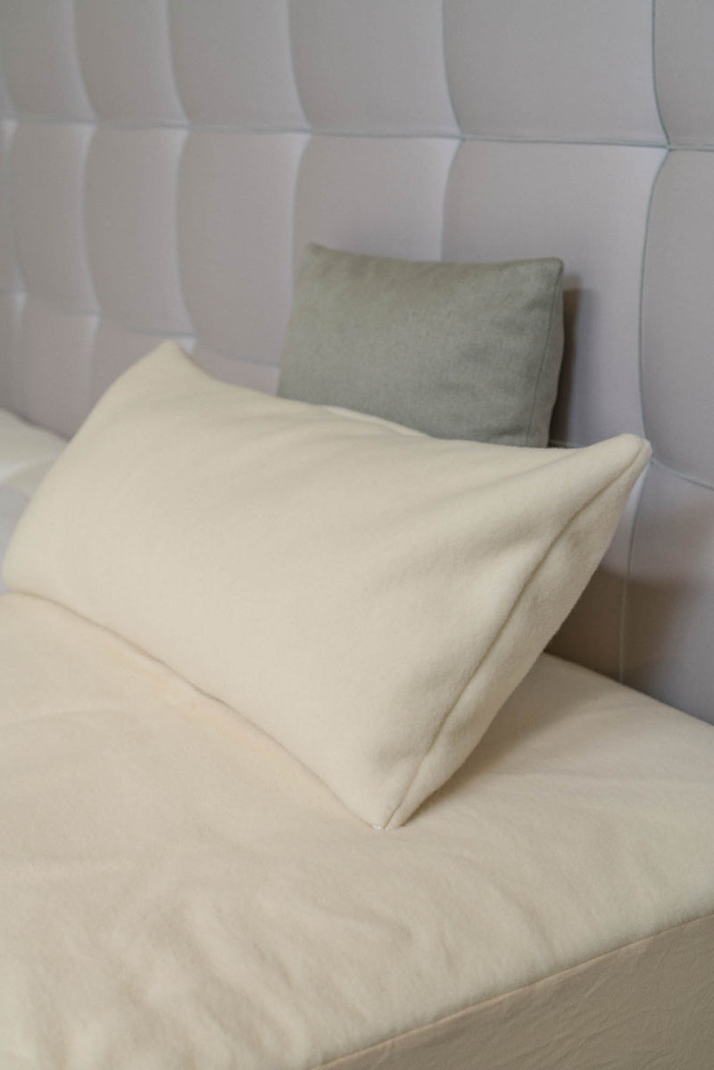 Kissenbezug Schurwolle in naturweiß auf dem Bett
