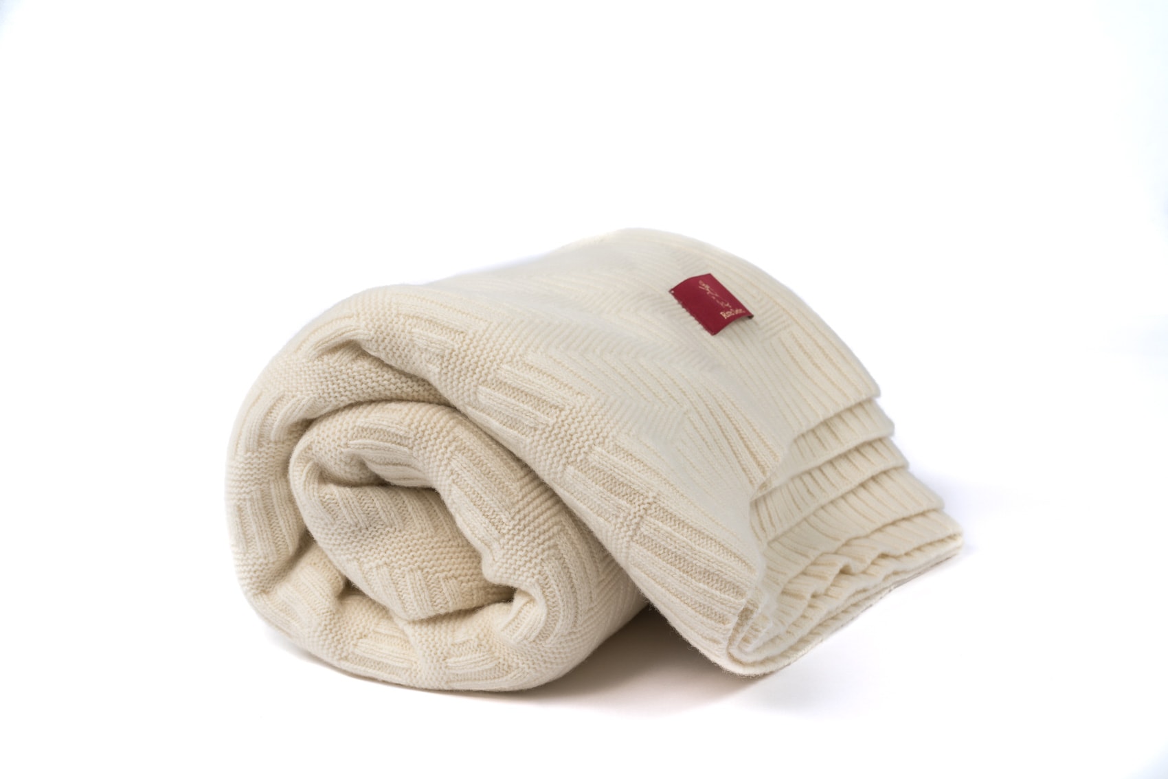 Gerolltes Porto Strickplaid in naturweiß mit Rautenmuster